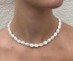 Collar Nácar de cuentas ovaladas de nácar natural, mostrado sobre el cuello de una modelo.