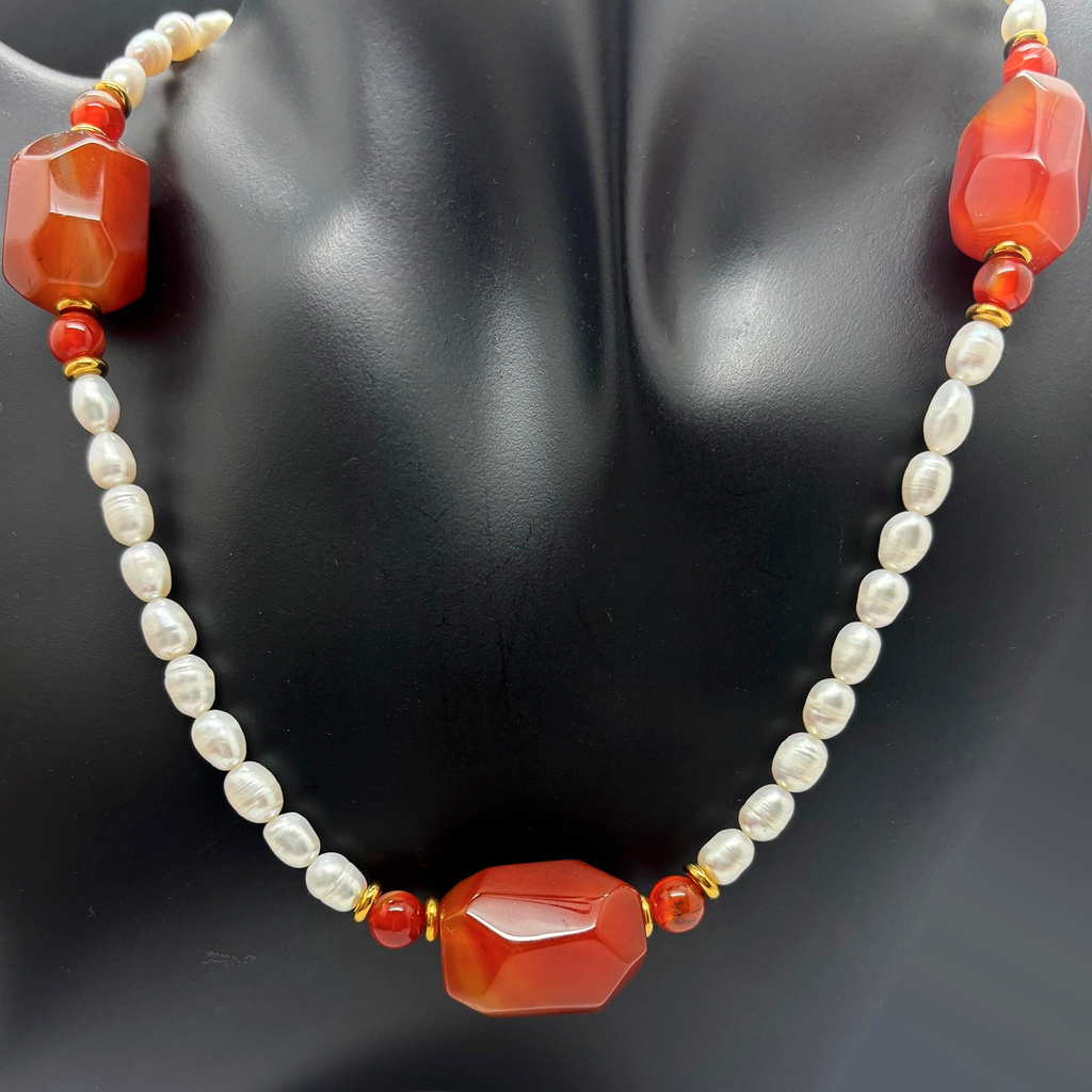 Fotografía real del Collar Calella sobre busto negro, con perlas de río cultivadas, cornalina en tonos naranja rojizo y detalles dorados.