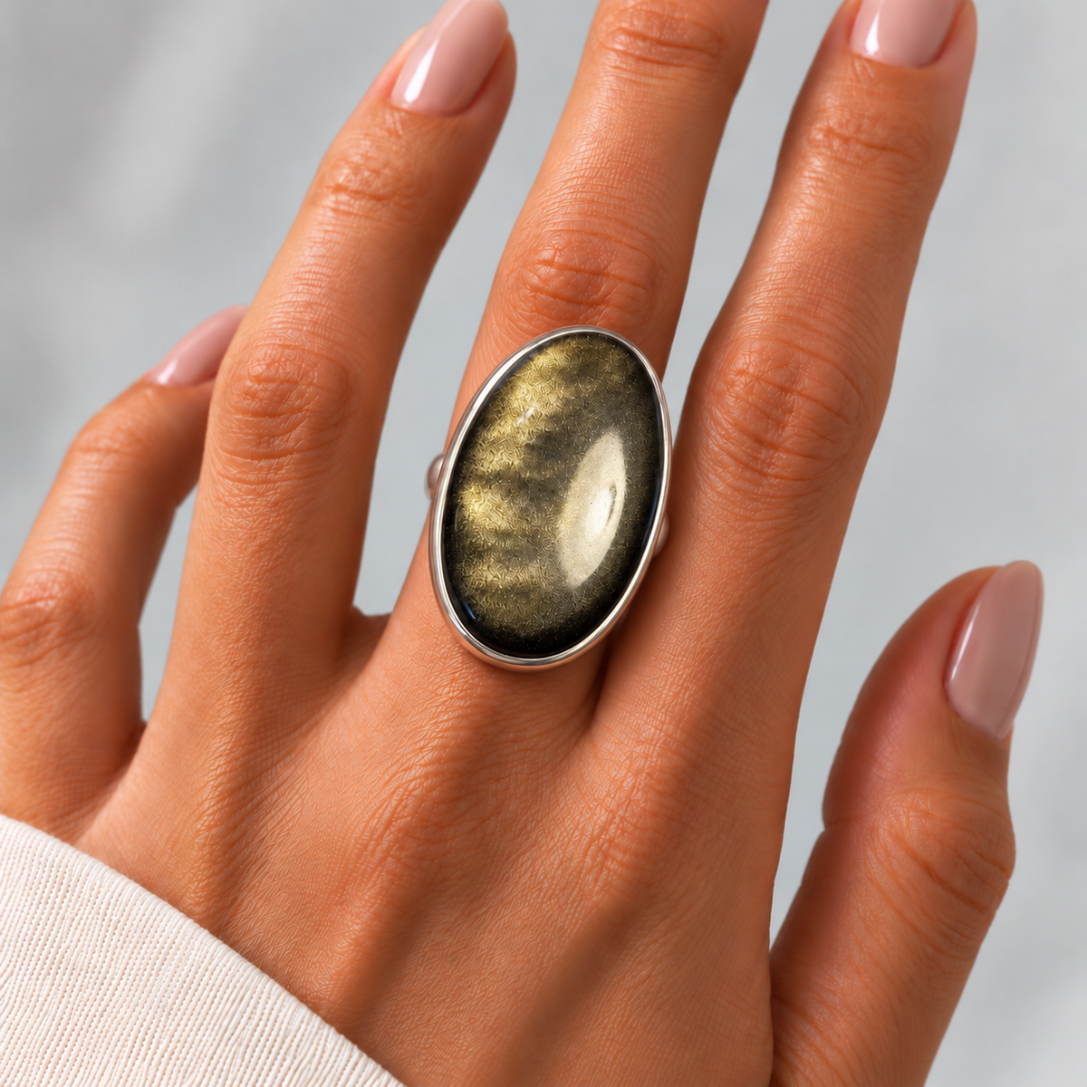 Anillo México de plata 925 con obsidiana dorada natural, centrado y alineado en el dedo de una modelo con manicura natural.