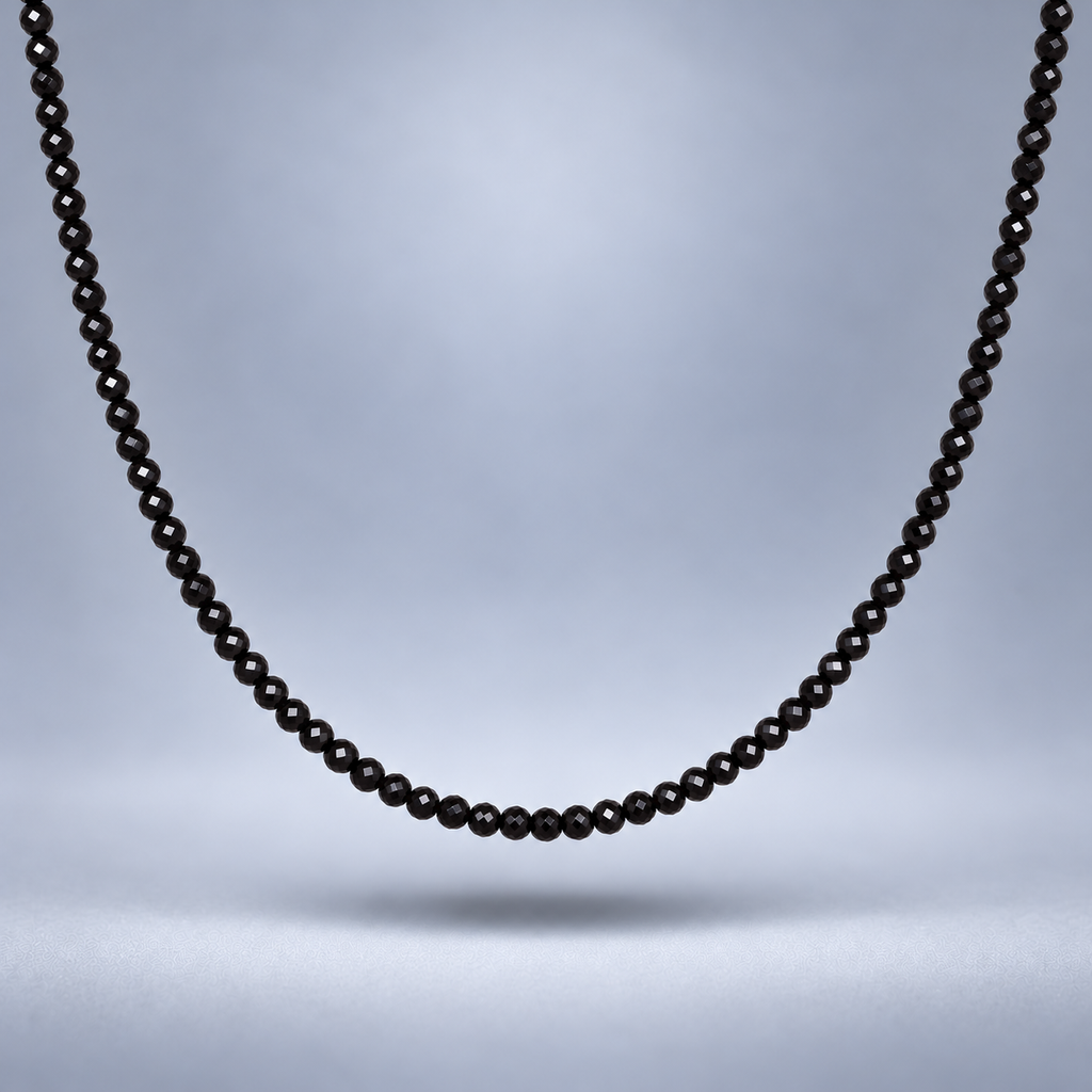 Detalle del choker de ónix negro facetado de 3 mm, suspendido sobre fondo gris suave con sombra y encuadre cercano.