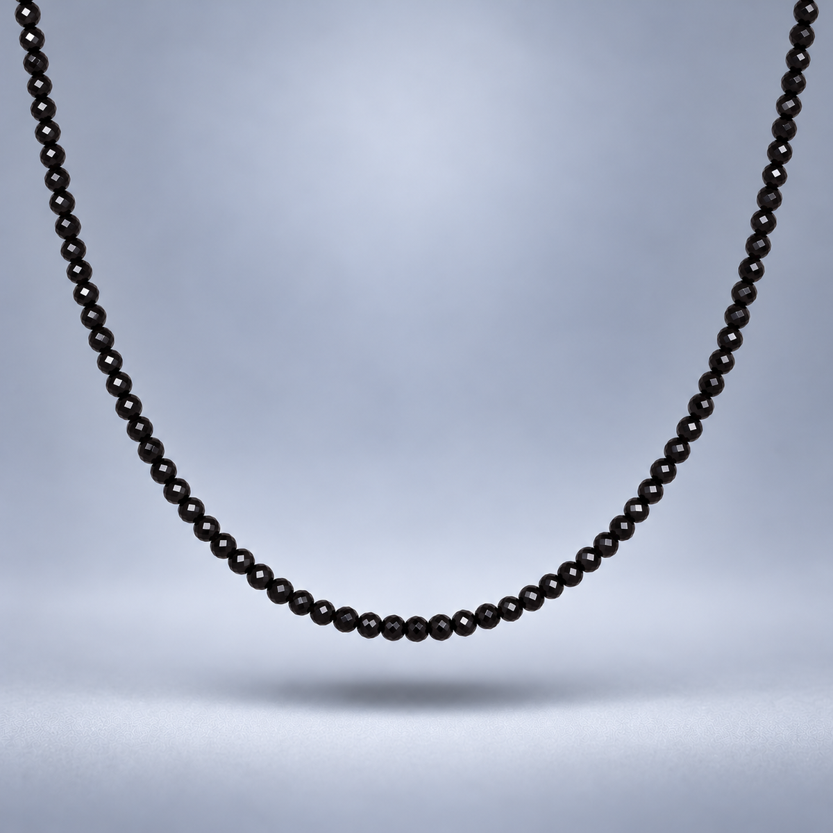 Detalle del choker de ónix negro facetado de 3 mm, suspendido sobre fondo gris suave con sombra y encuadre cercano.