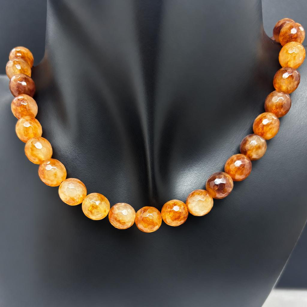 Fotografía del collar Empordà sobre busto negro, con cuentas redondas facetadas de ágata en tonos miel, caramelo y marrón.