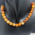 Fotografía del collar Empordà sobre busto negro, con cuentas redondas facetadas de ágata en tonos miel, caramelo y marrón.