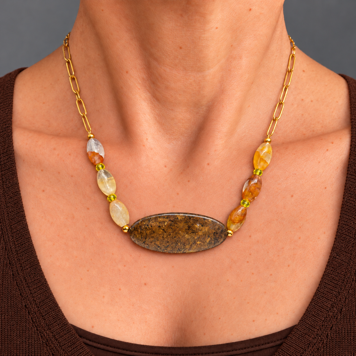Collar Ocre con broncita, cuarzo rutilado y citrino sobre el cuello de una modelo con jersey marrón chocolate.