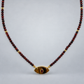 Collar de ojo de tigre y rubí reconstituido, suspendido sobre fondo gris claro.
