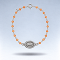 Pulsera Alma de plata con cornalina naranja pastel y medalla de la Virgen con circonitas, suspendida sobre fondo gris claro
