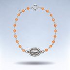Pulsera Alma de plata con cornalina naranja pastel y medalla de la Virgen con circonitas, suspendida sobre fondo gris claro