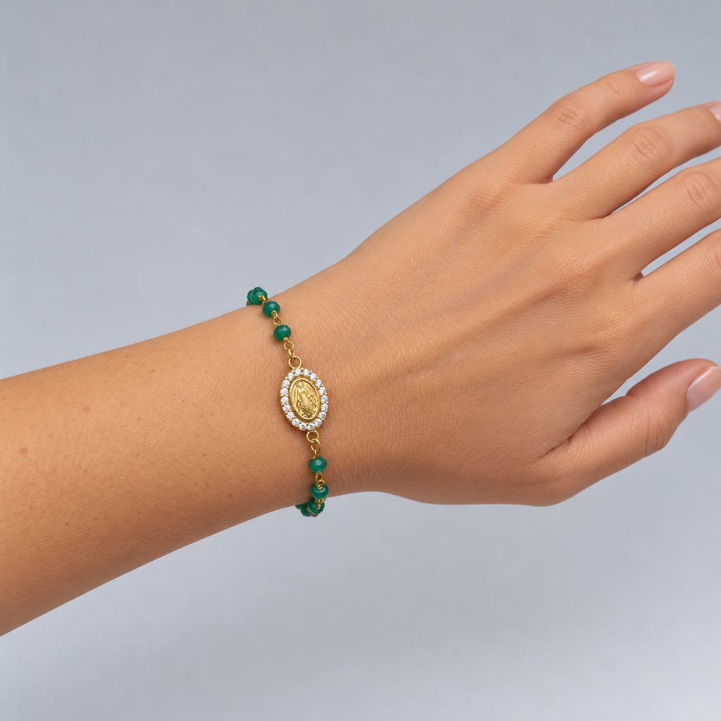 Pulsera de ónix verde con medalla de la Virgen y circonitas en la muñeca de una modelo, con la mano y parte del brazo visibles