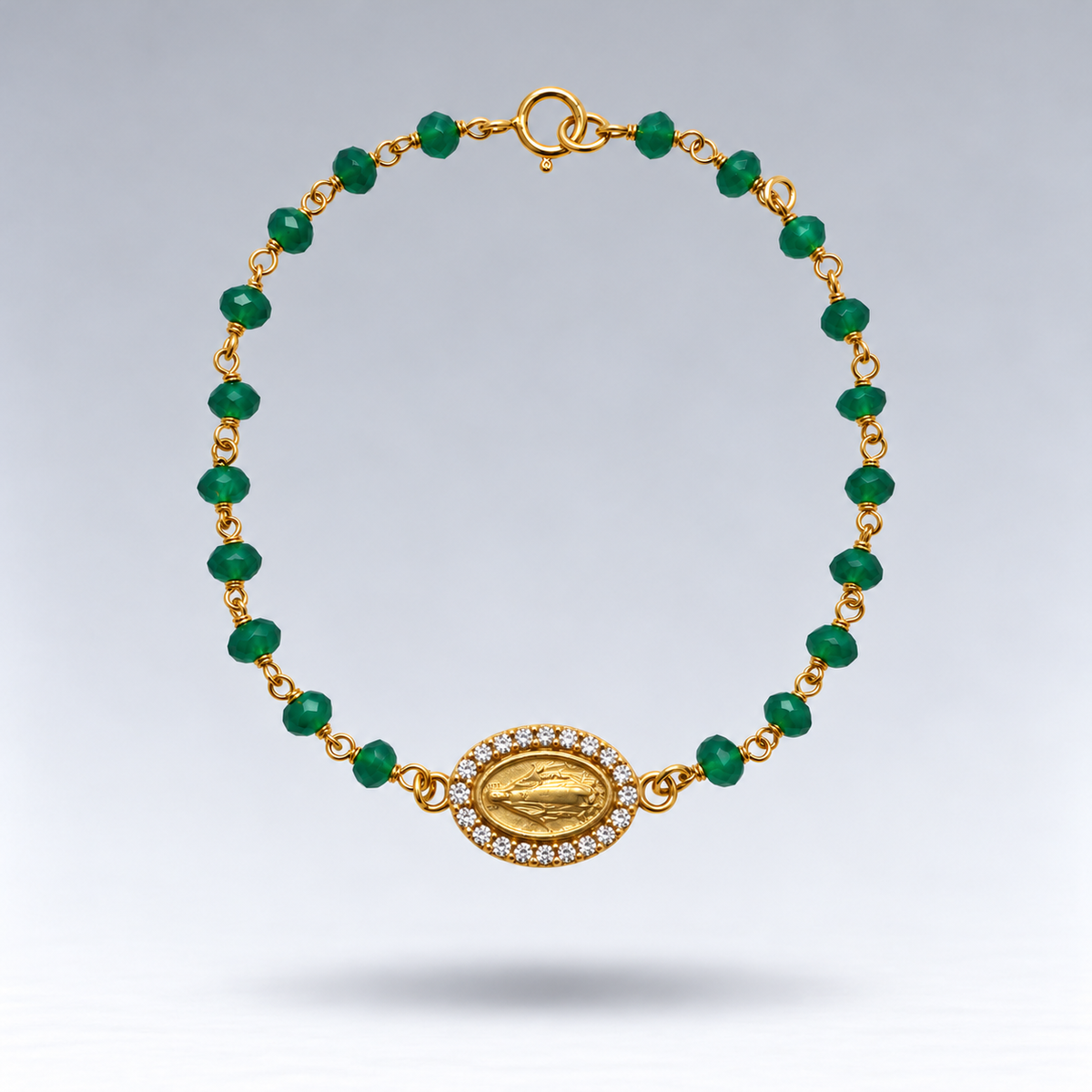 Pulsera Esperanza de ónix verde y plata chapada en oro con medalla de la Virgen y circonitas, suspendida sobre fondo gris claro